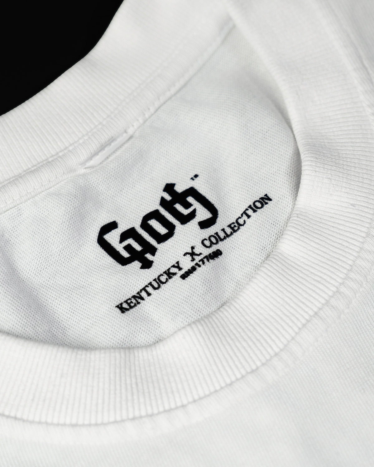 Printed GOTH neck label reading Kentucky × Collection, on a pigment white tee