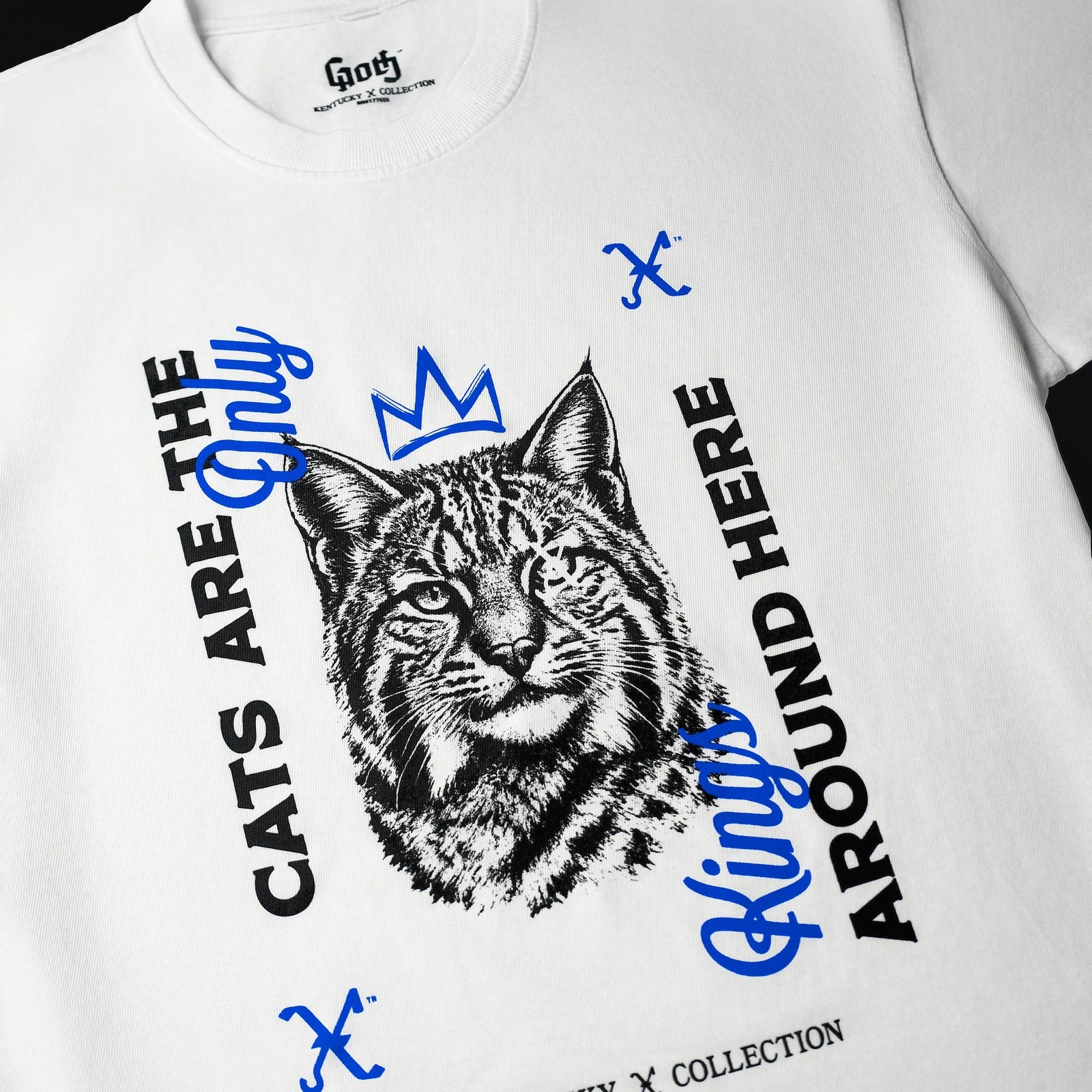 A white Wildcat Tee shows the printed crowned wildcat, blue script, and the Crook × Flail marking its eye.